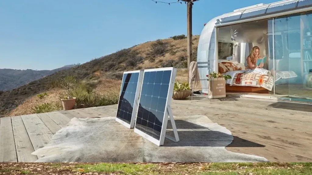 Paneles solares portátiles junto a una caravana en un camping