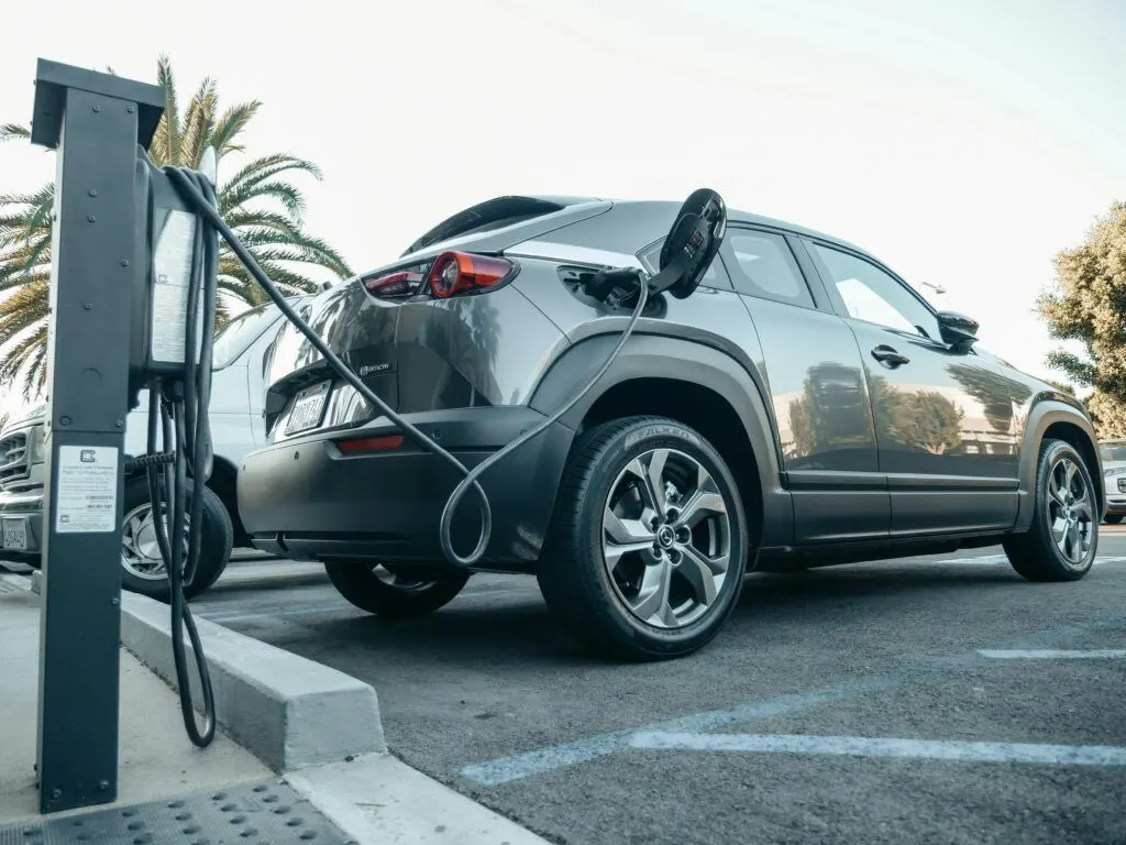Coche eléctrico todocamino gris conectado a un punto de recarga en un aparcamiento