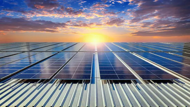 Placas solares sobre la cubierta metálica de una nave al atardecer